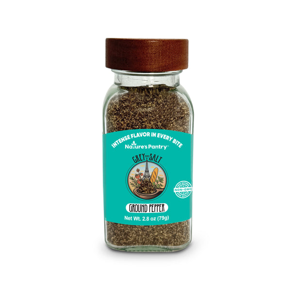 Glass jar of ground pepper with a brown lid on a white background
