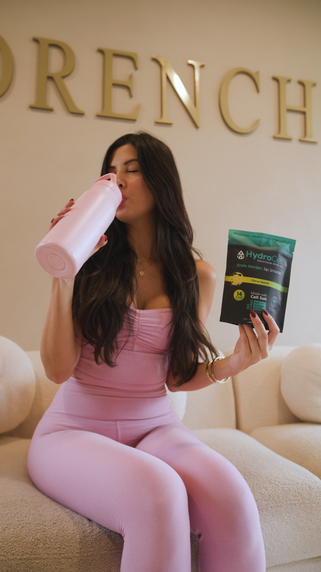 Woman in pink outfit holding a pink water bottle and HydroCelt package.