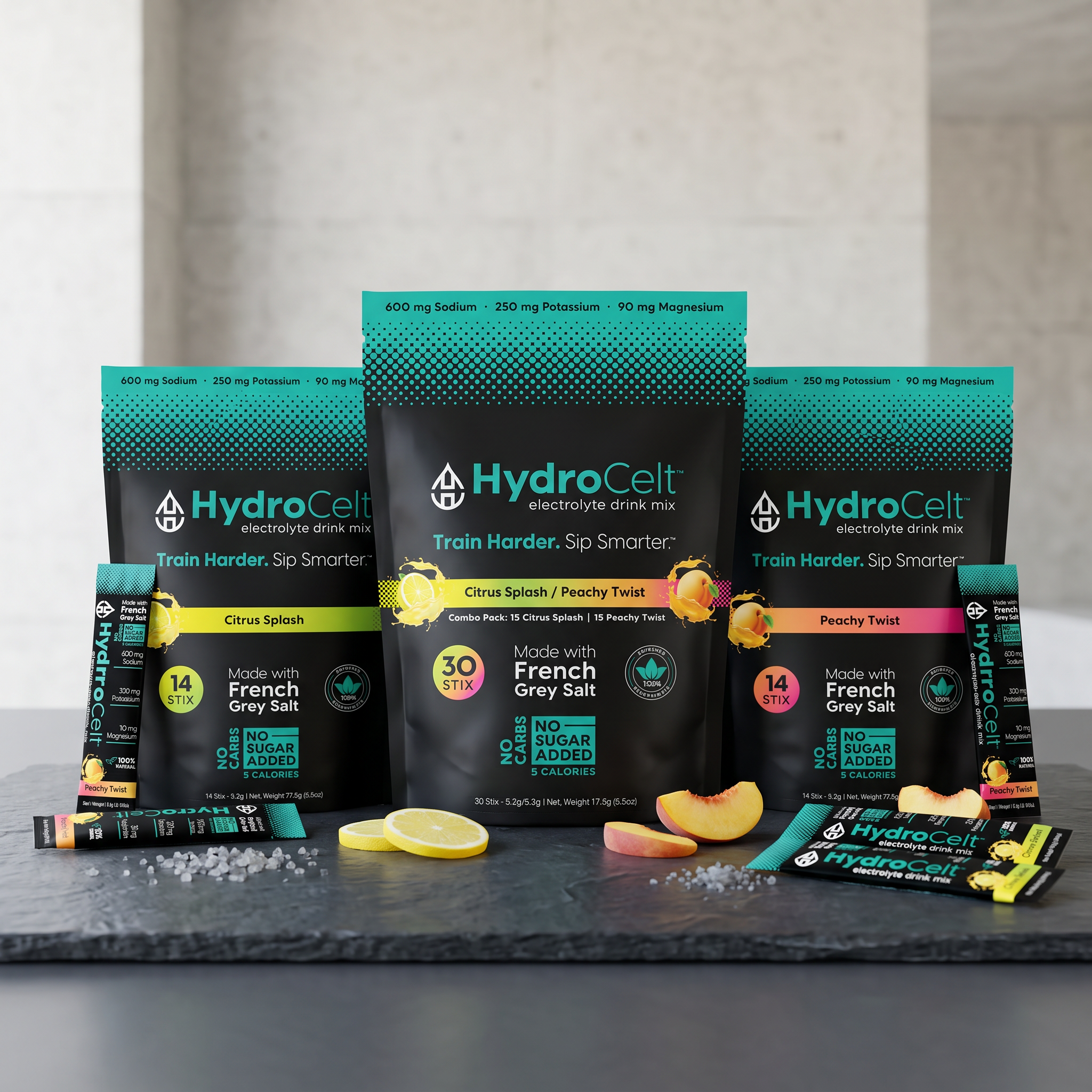 HydroCelt electrolyte drink mix packages on a gray surface with lemon slices and peach pieces.